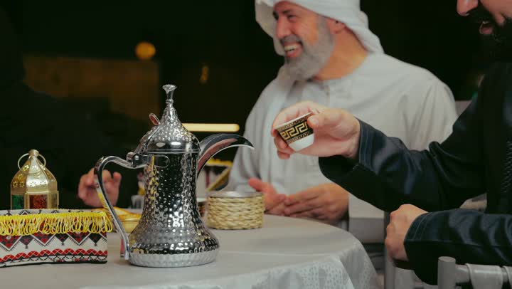 قضاء أوقات ممتعة في جلسة خارجية في احدى الاستراحات، تبادل الأحاديث والتسامر بين الأفراد، أجواء عائلية سعيدة في شهر رمضان المبارك، رجل عربي خليجي اماراتي يرتدي الزي التقليدي يقوم الاستمتاع بتناول المقهوه