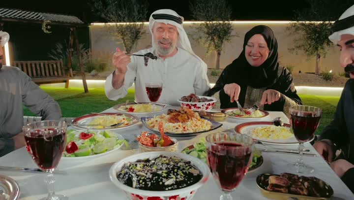 قضاء وقت ممتع في الاستراحة فى الامارات العربية, الزيارات والتجمعات الأسريه , تصوير لزوجان عربيان خليجان اماراتيان يرتدون الزي التقليدي يقومون بتناول الطعام الشهي, أجواء عائليه سعيده, المناسبات والاعياد الاسلاميه، سفرة من المأكولات الشعبية التقليدية الشهية