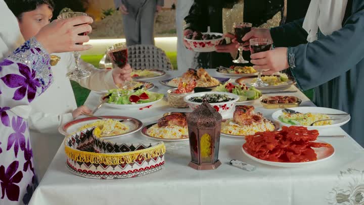 Performing the ritual of fasting in the holy month of Ramadan, a table filled with delicious oriental foods, a happy Ramadan religious family atmosphere, an Arab Gulf Emirati family gathered around the dining table, Islamic event decorations, enjoying fresh drinks