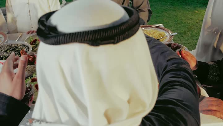 Family gatherings in Ramadan, preparing for the Iftar meal in the month of goodness and blessings, healthy foods on the Iftar table, a photo from behind of a man serving a plate of dates, a spiritual Ramadan atmosphere, Islamic and religious occasions