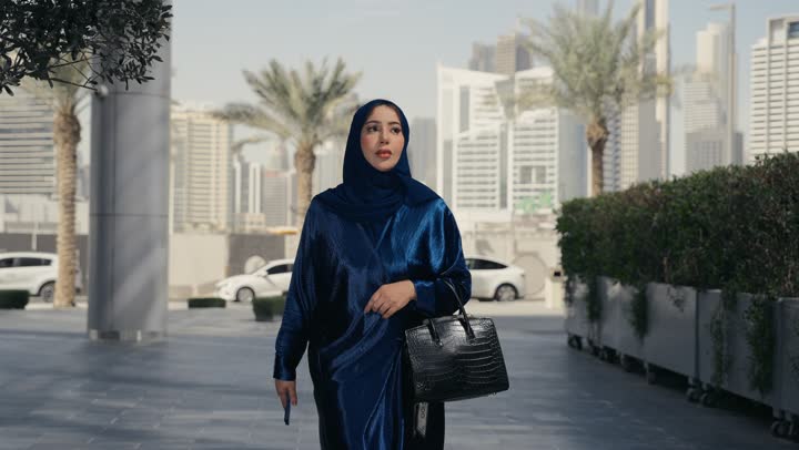 Concern for elegance and outward appearance, a veiled Saudi Arabian Gulf woman wearing a black abaya feeling ignorant and uninformed, an Emirati woman talking to someone on the phone, shopping and entertainment in the United Arab Emirates, a gesture of confusion and unfamiliarity with a place