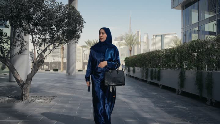 Concern for elegance and outward appearance, a veiled Saudi Arabian Gulf woman wearing a black abaya feeling ignorant and uninformed, an Emirati woman talking to someone on the phone, shopping and entertainment in the United Arab Emirates, a gesture of confusion and unfamiliarity with a place