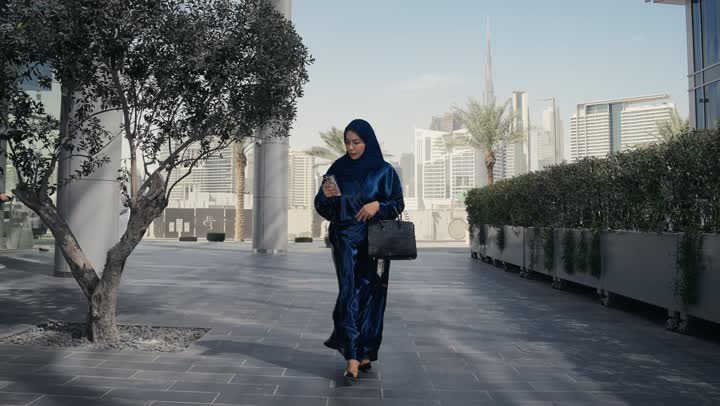 Concern for elegance and outward appearance, a veiled Saudi Arabian Gulf woman wearing a black abaya feeling ignorant and uninformed, an Emirati woman talking to someone on the phone, shopping and entertainment in the United Arab Emirates, a gesture of confusion and unfamiliarity with a place