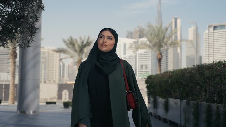 Veiled Saudi Arabian Gulf woman wearing black abaya feeling ignorant and clueless, Emirati lady talking to someone on the phone, shopping and entertainment in the UAE, gesture of confusion and not knowing where