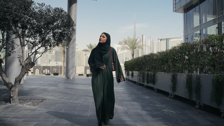 Veiled Saudi Arabian Gulf woman wearing black abaya feeling ignorant and clueless, Emirati lady talking to someone on the phone, shopping and entertainment in the UAE, gesture of confusion and not knowing where