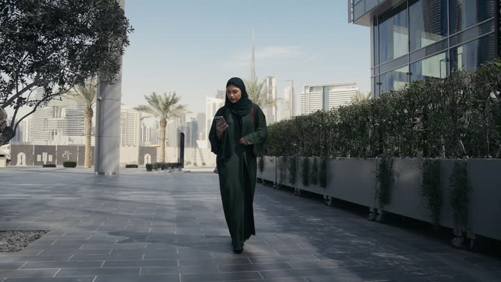Veiled Saudi Arabian Gulf woman wearing black abaya feeling ignorant and clueless, Emirati lady talking to someone on the phone, shopping and entertainment in the UAE, gesture of confusion and not knowing where