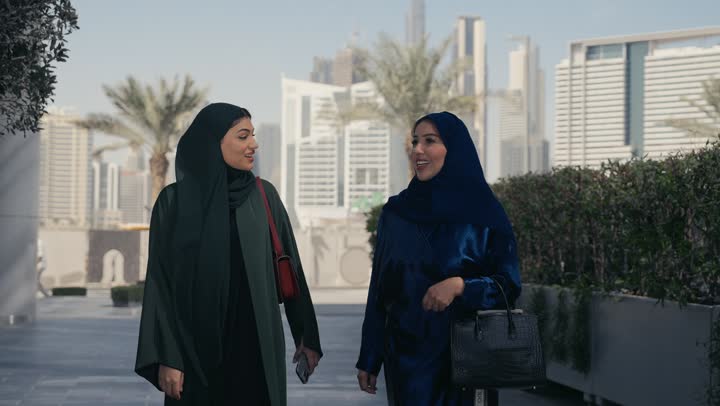 سيدتان عربيتان خليجيتان سعوديتان تشيران الي احد الاماكن، في احد صديقتان مبتسمتان تسيران معاً في نزهة ممتعة لإحدى الأماكن الترفيهية ، التنزه في وقت العطلة ، صداقات و تعارف ، علاقات إجتماعية ، كوفي شوب ، قضاء أوقات ممتعة