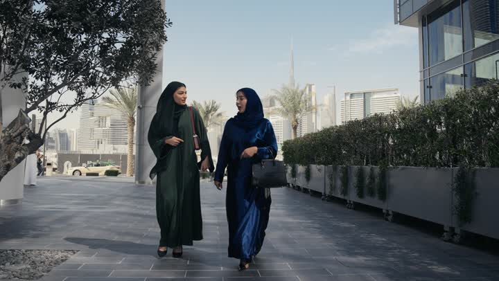 سيدتان عربيتان خليجيتان سعوديتان تشيران الي احد الاماكن، في احد صديقتان مبتسمتان تسيران معاً في نزهة ممتعة لإحدى الأماكن الترفيهية ، التنزه في وقت العطلة ، صداقات و تعارف ، علاقات إجتماعية ، كوفي شوب ، قضاء أوقات ممتعة