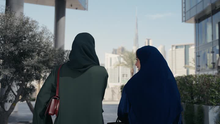 صديقتان اماراتيتان تحملان اكياس التسوق الملونه تسيران معاً في نزهة ممتعة لإحدى الأماكن الترفيهية، سيدتان خليجيتان سعوديتان ترتديان العباءة الخليجية تتحدثان عن السوالف، صداقات وتعارف، دردشة ومحادثات، قضاء وقت ممتع في الخارج