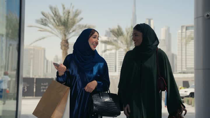 متعة مشاركة الأصدقاء في اختيار الهدايا من المحلات والمراكز التجارية في الجمعه البيضاء، صديقتان عربيتيان خليجيتان اماراتيتان تحملان الأكياس الورقية وتقومان بالتبضع في المول، الشراء من الماركات الاماراتيه الفاخرة، الأثر الإيجابي للتسوق على النساء