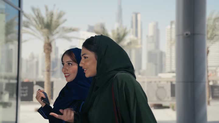 اختيار المستلزمات برفقة الأصدقاء, سيدتان عربيتان خليجيتان سعوديتان تحملان أكياس التسوق الملونه, صديقتان اماراتيتان تستمتعان بالتجول في المولات التجاريه في الامارات العربيه المتحده, التأثير الإيجابي للتسوق والشراء على السيدات, الاستفاده من العروض