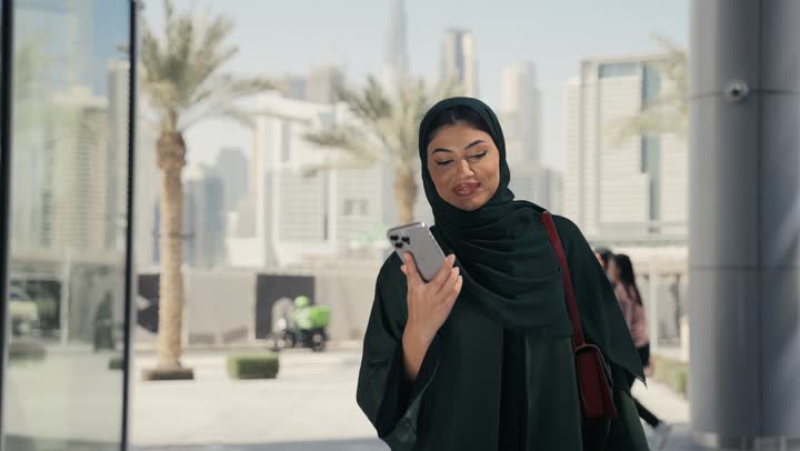The concept of femininity and softness, interest in elegance and outward appearance, elegant modern veiled fashion, a veiled Saudi Arabian Gulf woman wearing a black abaya standing in front of a clothing store, an Emirati woman taking pictures of some women's clothing, shopping and entertainment in the United Arab Emirates