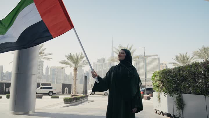 Emirati Gulf Arab woman wearing the Gulf abaya holding the UAE flag, UAE National Day, UAE National Day celebration, UAE National Day 51 identity, UAE Independence Day, love of the homeland