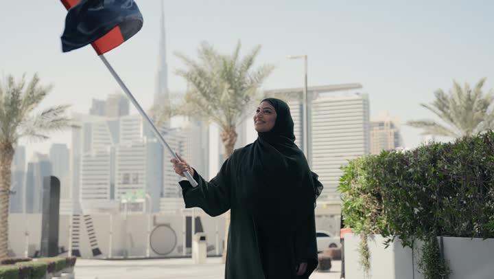Emirati Gulf Arab woman wearing the Gulf abaya holding the UAE flag, UAE National Day, UAE National Day celebration, UAE National Day 51 identity, UAE Independence Day, love of the homeland