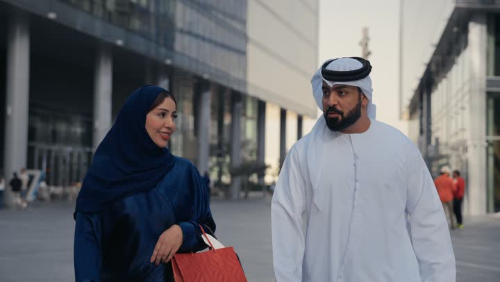 زوجان عربيان اماراتيان خليجيان سعيدان بالتسوق معا في المركز التجاري, سيدة جميلة وزوجها يحملان أكياس التسوق من المتجر, ماركات عالمية, التسوق في المول, متعة التسوق في الامارات العربيه المتحده