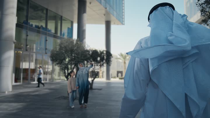أم عربية خليجية إماراتية ترتدي الحجاب والعباءة تقوم بالتجول في الهواء الطلق برفقة ابنتها، التنزه في وقت العطلة في إحدى الاماكن العامة في الإمارات, امرأة سعودية تقوم بالتقاط صور السيلفي التذكارية باستخدام الهاتف المحمول بإيماءات السعادة والسرور