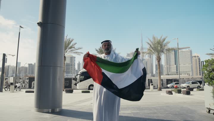 اليوم الوطني الاماراتي 1971، رجل عربي خليجي اماراتي يرتدي الكندرة الغترة التقليدية يقبل علم الامارات العربية المتحدة في النهار، الاحتفال بذكرى تأسيس الاتحاد 2 ديسمبر في الطريق، التجول في الهواء الطلق، يوم العلم 3 نوفمبر، حب الوطن والاعتزاز به