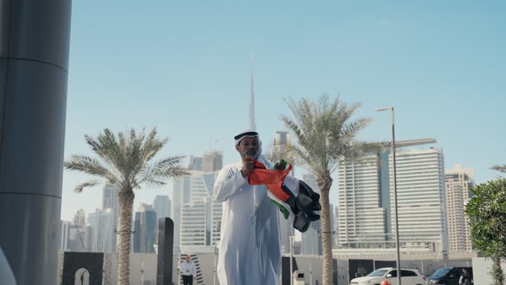 اليوم الوطني الاماراتي 1971، رجل عربي خليجي اماراتي يرتدي الكندرة الغترة التقليدية يقبل علم الامارات العربية المتحدة في النهار، الاحتفال بذكرى تأسيس الاتحاد 2 ديسمبر في الطريق، التجول في الهواء الطلق، يوم العلم 3 نوفمبر، حب الوطن والاعتزاز به