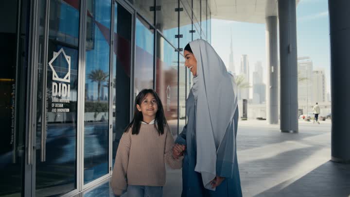 تبادل الأحاديث والأخبار بإيماءات السرور والفرح, عائلة سعودية تقوم بالتنزه في وقت العطلة في إحدى الاماكن العامة في الإمارات, أم عربية خليجية إماراتية ترتدي الحجاب والعباءة تقوم بالمشي والتجول في الهواء الطلق برفقة ابنتها، الاشارة إلى شيء ما، تقديم الاهتمام للأبناء