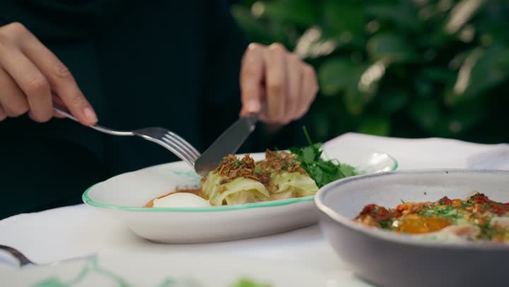 Restaurants and cafes in the Emirates, delicious dishes and foods, gestures of happiness and pleasure, enjoying recreational activities, spending fun times outside, having lunch at the restaurant, a close-up shot from above of a veiled Emirati Gulf Arab woman wearing casual clothes sitting at the table