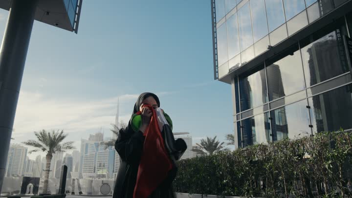 Pride, dignity and honor, UAE National Independence Day, Emirati woman holding the UAE flag and kissing it, UAE National Day commemoration, Emirati woman wearing a black abaya celebrating UAE National Day