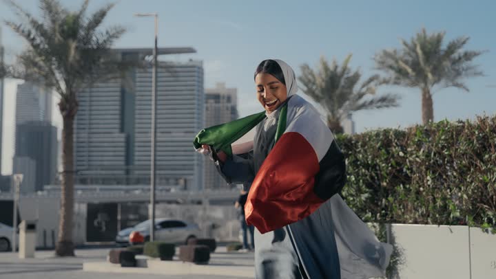 Pride and appreciation for the country's achievements, the identity of the 51st UAE National Day, celebrating the UAE National Day, UAE Independence Day, love and belonging to the homeland, an Arab Gulf Emirati woman hugging the UAE flag, gestures of love and pride