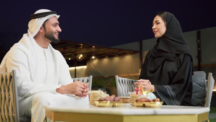 الجلوس في إحدى الشاليهات الاماراتية الراقية، شرب القهوة العربية، قضاء أوقات عائلية ممتعة, التفاهم والترابط الفكري بين الزوجين، تناول الوجبات الخفيفة والتسالي، زوجان عربيان خليجيان اماراتيان يجلسان في الهواء الطلق ويقومان بتبادل الأحاديث