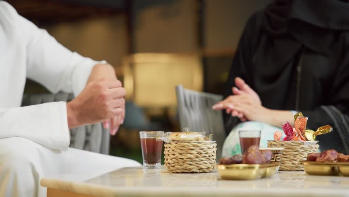 الجلوس في إحدى الشاليهات الاماراتية الراقية، شرب القهوة العربية، قضاء أوقات عائلية ممتعة, التفاهم والترابط الفكري بين الزوجين، تناول الوجبات الخفيفة والتسالي، زوجان عربيان خليجيان اماراتيان يجلسان في الهواء الطلق ويقومان بتبادل الأحاديث