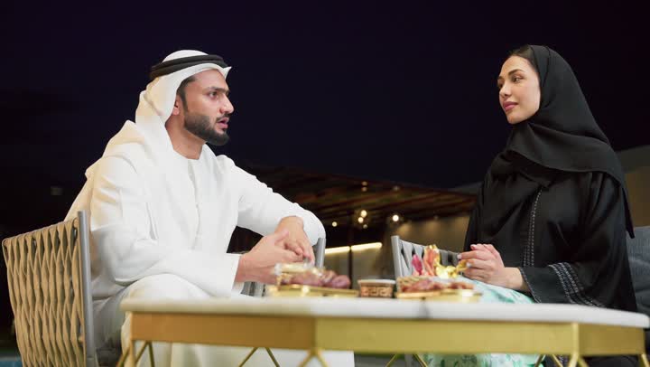 الجلوس في إحدى الشاليهات الاماراتية الراقية، شرب القهوة العربية، قضاء أوقات عائلية ممتعة, التفاهم والترابط الفكري بين الزوجين، تناول الوجبات الخفيفة والتسالي، زوجان عربيان خليجيان اماراتيان يجلسان في الهواء الطلق ويقومان بتبادل الأحاديث