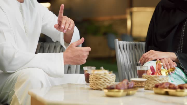 الجلوس في إحدى الشاليهات الاماراتية الراقية، شرب القهوة العربية، قضاء أوقات عائلية ممتعة, التفاهم والترابط الفكري بين الزوجين، تناول الوجبات الخفيفة والتسالي، زوجان عربيان خليجيان اماراتيان يجلسان في الهواء الطلق ويقومان بتبادل الأحاديث