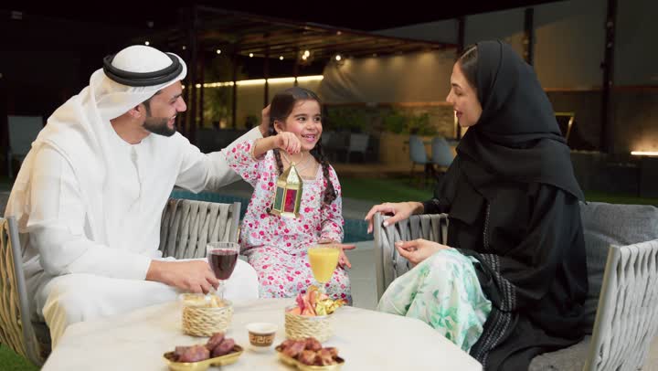 ايماءات السعادة بقدوم رمضان، قضاء وقت ممتع في جلسة خارجية عائلية في احدى الشاليهات، زينة واكسسوار الأعياد والمناسبات الاسلامية، فتاة عربية خليجية اماراتية تحمل بيدها فانوس معدني مزخرف مضيء بجانب والديها، ضيافة شهر رمضان المبارك، أجواء ليلية رمضانية روحانية