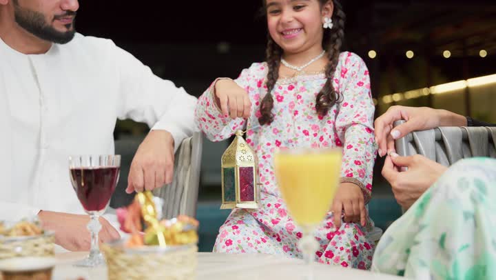 ايماءات السعادة بقدوم رمضان، قضاء وقت ممتع في جلسة خارجية عائلية في احدى الشاليهات، زينة واكسسوار الأعياد والمناسبات الاسلامية، فتاة عربية خليجية اماراتية تحمل بيدها فانوس معدني مزخرف مضيء بجانب والديها، ضيافة شهر رمضان المبارك، أجواء ليلية رمضانية روحانية
