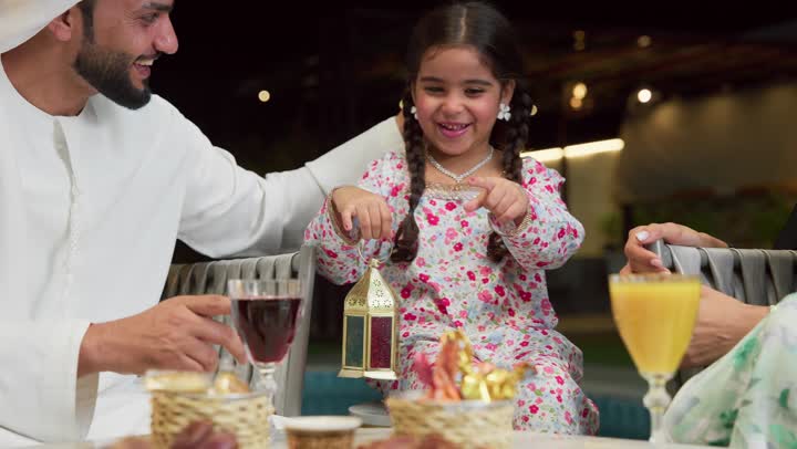 ايماءات السعادة بقدوم رمضان، قضاء وقت ممتع في جلسة خارجية عائلية في احدى الشاليهات، زينة واكسسوار الأعياد والمناسبات الاسلامية، فتاة عربية خليجية اماراتية تحمل بيدها فانوس معدني مزخرف مضيء بجانب والديها، ضيافة شهر رمضان المبارك، أجواء ليلية رمضانية روحانية