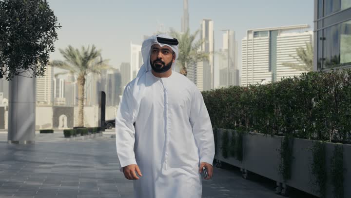 Walking around and enjoying the fresh air, a walk in the open air, an Emirati Gulf Arab man wearing a kandura and ghutra spending a pleasant time in one of the parks in the Emirates, a tour in nature, walking around public areas