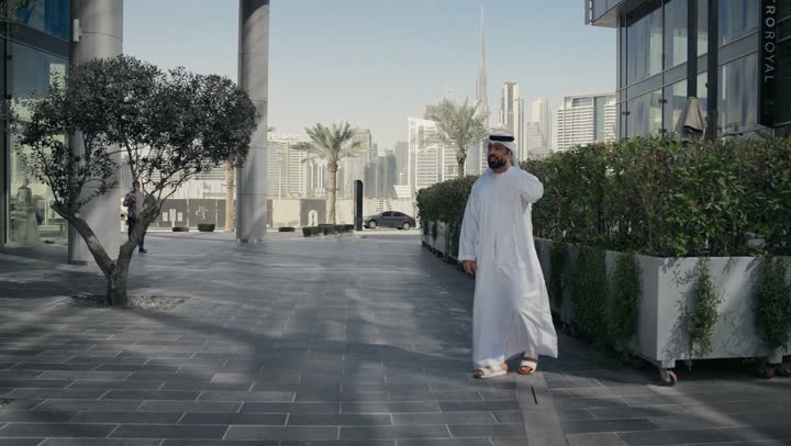 رجل عربي خليجي اماراتي يقضي أوقات ممتعة في إحدى الحدائق في الامارات ، جولة في الطبيعة، نزهه في الهواء الطلق، الدردشة والتواصل مع العائلة ، سماع الاخبار والمفاجأت السعيدة،إجراء مكالمه هاتفيه عبر الهاتف المحمول