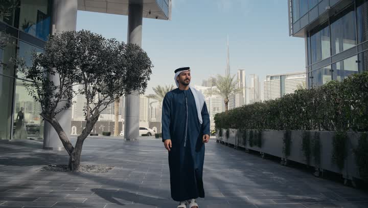Walking around and enjoying the fresh air, a walk in the open air, an Emirati Gulf Arab man wearing a kandura and ghutra having a good time in one of the parks in the Emirates, a nature walk, walking around public areas