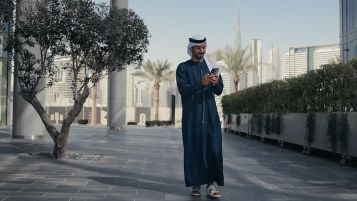 الدردشة والتواصل مع العائلة ،إجراء مكالمه هاتفيه عبر الهاتف المحمول، رجل عربي خليجي اماراتي يقضي أوقات ممتعة في إحدى الحدائق في الامارات ، جولة في الطبيعة، نزهه في الهواء الطلق، سماع الاخبار والمفاجأت السعيدة