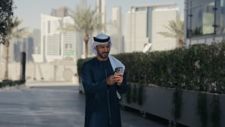 إجراء مكالمه هاتفيه عبر الهاتف المحمول، رجل عربي خليجي اماراتي يقضي أوقات ممتعة في إحدى الحدائق في الامارات ، جولة في الطبيعة، نزهه في الهواء الطلق، الدردشة والتواصل مع العائلة ، سماع الاخبار والمفاجأت السعيدة