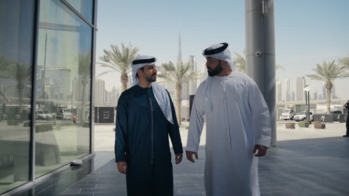 النظر الى بعضهما بتعابير السرور، مفهوم الأناقة والاهتمام بالمظهر الخارجي ،الاستمتاع والتجول مع الاصدقاء ، قضاء اوقات ممتعه ، المشي فى الخارج ، استنشاق الهواء النقي في وقت النهار، صديقان عربيان خليجيان اماراتيان يرتديان الكندوره والغتره