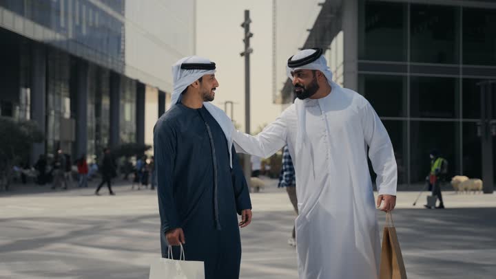 مفهوم الأناقة والاهتمام بالمظهر الخارجي ، تقوية وتعزيز العلاقات الاجتماعية ، اشارات تحدد هذا المكان (هنا) ، صديقان عربيان خليجيان اماراتيان يرتديان الكندوره والغتره، قضاء أوقات ممتعة في الطبيعة ، النظر الى شئ ما بتعابير السرور ، استنشاق الهواء النقي في وقت النهار .