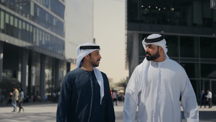 تقوية وتعزيز العلاقات الاجتماعية ، اشارات تحدد هذا المكان (هنا) ، صديقان عربيان خليجيان اماراتيان يرتديان الكندوره والغتره، قضاء أوقات ممتعة في الطبيعة ، النظر الى شئ ما بتعابير السرور ، مفهوم الأناقة والاهتمام بالمظهر الخارجي ، استنشاق الهواء النقي في وقت النهار .