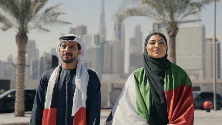 يوم استقلال الإمارات ، التعرف على ثقافات وتاريخ شعب الامارات، حب الوطن والانتماء إليه, الاحتفال باليوم الوطني 2 ديسمبر، تصوير لزوجان يرتديان الزى الاماراتي يضعان علم دولة الامارات العربية المتحدة على الكتف