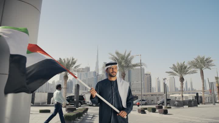ايماءات الفخر والسعاده ، إحياء ذكرى استقلال البلاد، يوم استقلال الإمارات ، التعرف على ثقافات وتاريخ شعب الامارات، حب الوطن والانتماء إليه, الاحتفال باليوم الوطني 2 ديسمبر، تصوير لرجل يرتدي الكندوره والغتره يرفع علم دولة الامارات العربية المتحدة
