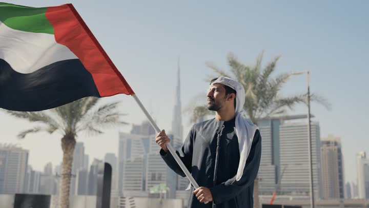 حب الوطن والانتماء إليه, تصوير لرجل يرتدي الكندوره والغتره يرفع علم دولة الامارات العربية المتحدة ، ايماءات الفخر والسعاده ، إحياء ذكرى استقلال البلاد، يوم استقلال الإمارات ، التعرف على ثقافات وتاريخ شعب الامارات، الاحتفال باليوم الوطني 2 ديسمبر
