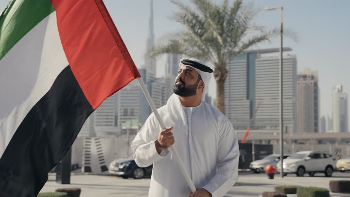 ذكرى تأسيس الاتحاد1971، التعرف على ثقافات وتاريخ شعب الامارات، إحياء ذكرى استقلال البلاد، ايماءات الفخر والسعاده ، حب الوطن والانتماء إليه, تصوير لرجل يرتدي الكندوره والغتره يرفع علم دولة الامارات العربية المتحدة ،  يوم استقلال الإمارات ، الاحتفال باليوم الوطني 2 ديسمبر