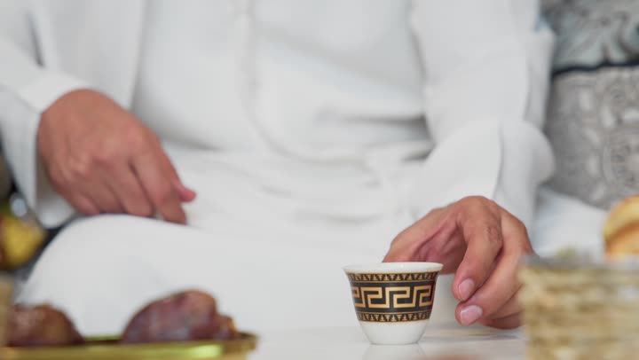 دمج التكنولوجيا فى الحياه اليوميه، الاطمئنان على الاهل والاصدقاء ،ضيافة شهر رمضان المبارك،جلسة الليلة الخارجية في احدى شاليهات الامارات ، تكنولوجيا وتقنيات حديثه ،شاب عربي خليجي اماراتي يرتدي الكندورة والغترة يستخدم الجوال يجلس في الهواء الطلق