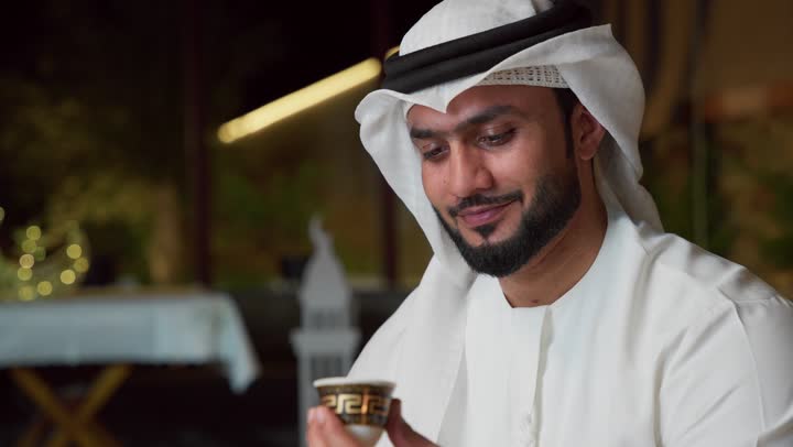 الاطمئنان على الاهل والاصدقاء ، دمج التكنولوجيا فى الحياه اليوميه، ضيافة شهر رمضان المبارك،جلسة الليلة الخارجية في احدى شاليهات الامارات ، تكنولوجيا وتقنيات حديثه ،شاب عربي خليجي اماراتي يرتدي الكندورة والغترة يستخدم الجوال يجلس في الهواء الطلق