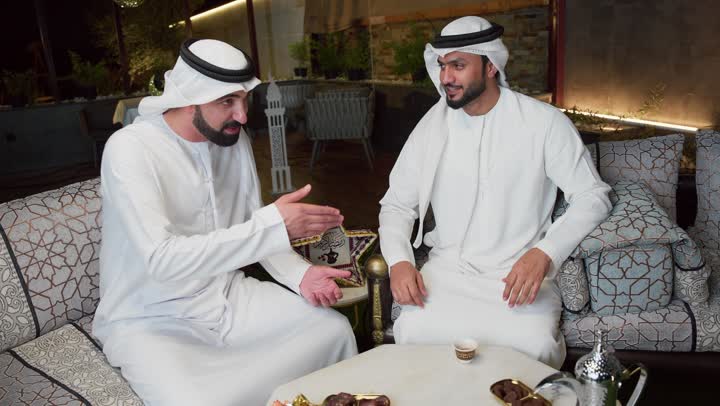استنشاق الهواء النقي ، الاستمتاع بالاجواء الرمضانيه السعيده ، قضاء اوقات ممتعه مع الاصدقاء الجلسة الليلة الخارجية في احدى شاليهات الامارات، عادات وتقاليد شرب القهوة التقليدية، حسن الاستقبال والكرم في شهر رمضان المبارك، صديقان عربيان خليجيان اماراتيان يرتديان الكندورة والغترة يجلسان في الهواء الطلق