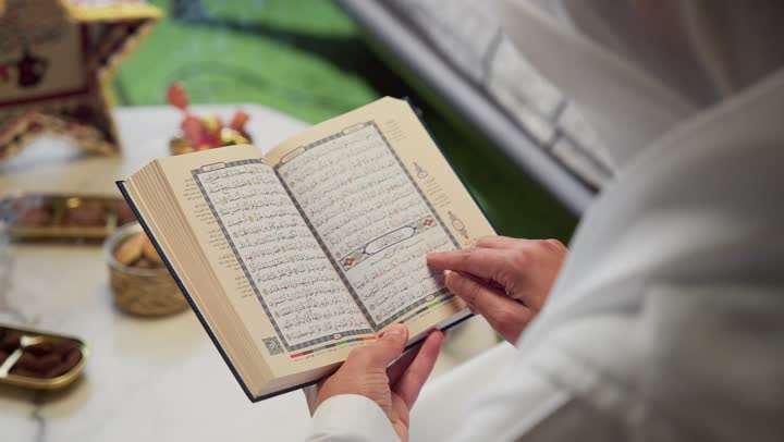 الشعور بالخشوع والطمأنينة، الجلوس فى احدي الشاليهات الاماراتيه ، الإكثار من ذكر الله تعالى، تلاوة وقراءة القرآن الكريم وتدبر معانيه، الاجتهاد في العبادة، شاب عربي خليجي اماراتي يرتدي الكندوره والغتره يحمل بيده المصحف الشريف، التقرب الى الله في شهر رمضان