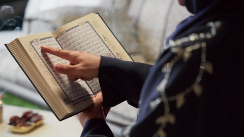 جلسات خارجية في الهواء الطلق ، إستقبال شهر رمضان، المناسبات الدينية والأعياد الإسلامية، امراه عربية خليجية اماراتيه ترتدي العباءه والحجاب تمسك بيدها القران الكريم ، أجواء رمضانية ،كتاب الله تعالى ، تلاوة وتحفيظ القرآن الكريم ، أدعية وأذكار، زينة شهر رمضان، قراءة القرآن الكريم